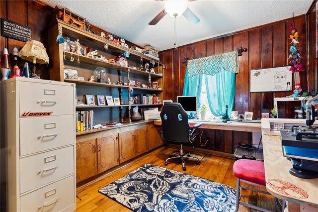 office area featuring light wood-type flooring, ceiling fan, and wood walls