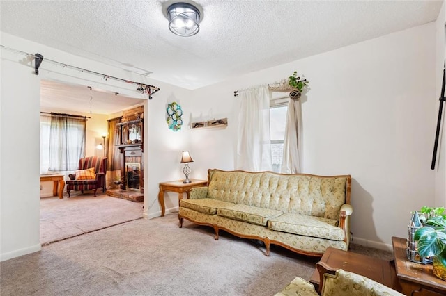 living room with a brick fireplace, carpet floors, and a textured ceiling