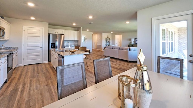 kitchen featuring white cabinets, stainless steel appliances, wood finished floors, and a sink