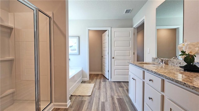 full bathroom with a bath, wood finished floors, visible vents, and a stall shower
