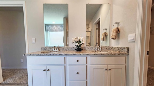 bathroom featuring baseboards, a sink, and double vanity