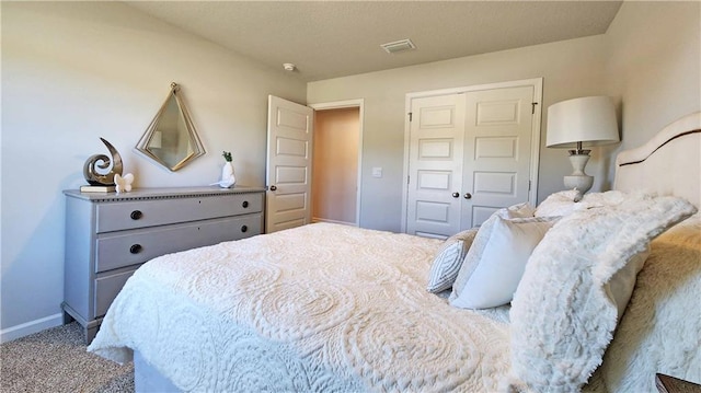 bedroom with a closet, carpet floors, visible vents, and baseboards