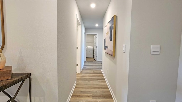corridor featuring light wood-type flooring, baseboards, recessed lighting, and washer / dryer