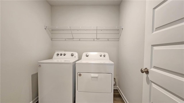 clothes washing area featuring washing machine and clothes dryer, wood finished floors, laundry area, and baseboards