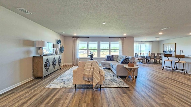 living room featuring a textured ceiling, wood finished floors, and visible vents