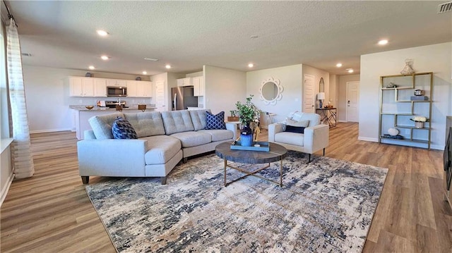 living area with visible vents, light wood-style flooring, and baseboards