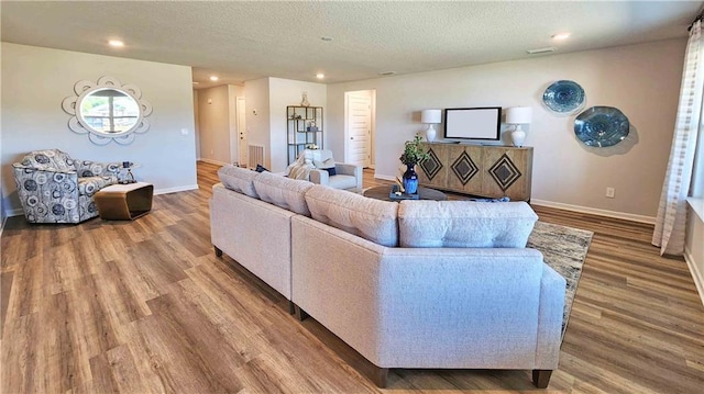 living area featuring recessed lighting, wood finished floors, a textured ceiling, and baseboards