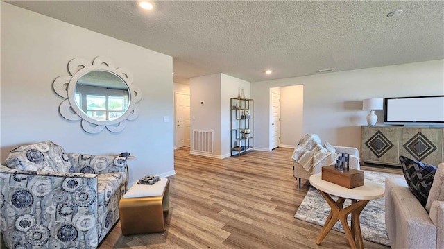 living room with recessed lighting, wood finished floors, visible vents, baseboards, and a textured ceiling