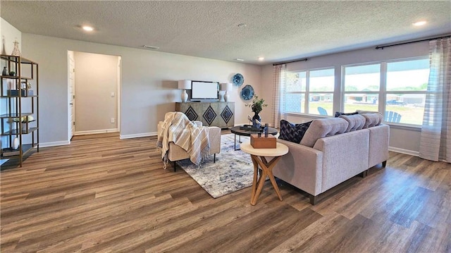 living area with wood finished floors, a textured ceiling, and baseboards
