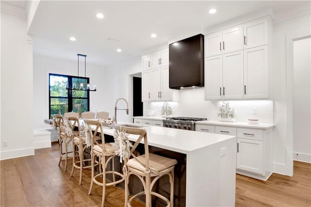 kitchen featuring white cabinets, a kitchen bar, and an island with sink