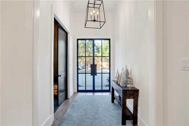 doorway to outside featuring wood-type flooring, crown molding, and an inviting chandelier