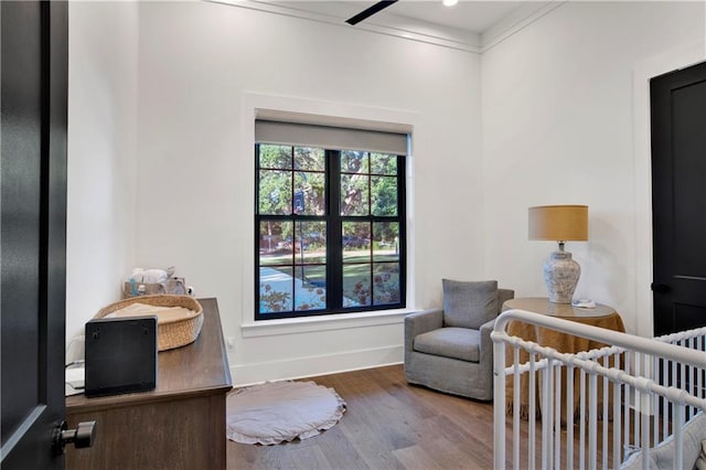 bedroom featuring crown molding, a nursery area, and hardwood / wood-style flooring