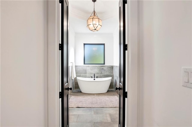 bathroom featuring a washtub, tile patterned flooring, tile walls, and ornamental molding