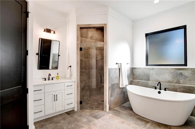 bathroom with vanity, crown molding, tile walls, and plus walk in shower