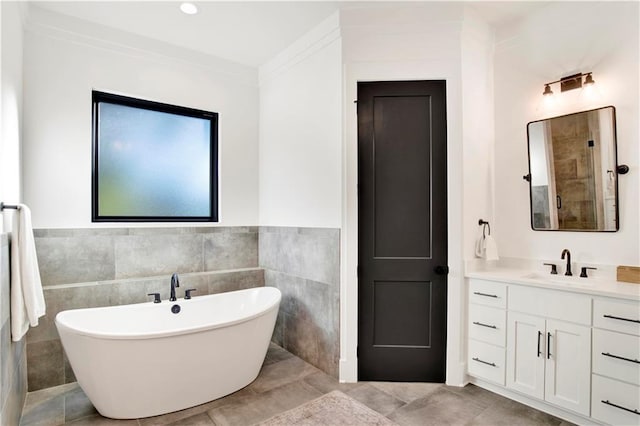 bathroom featuring tile patterned flooring, vanity, a tub to relax in, and tile walls