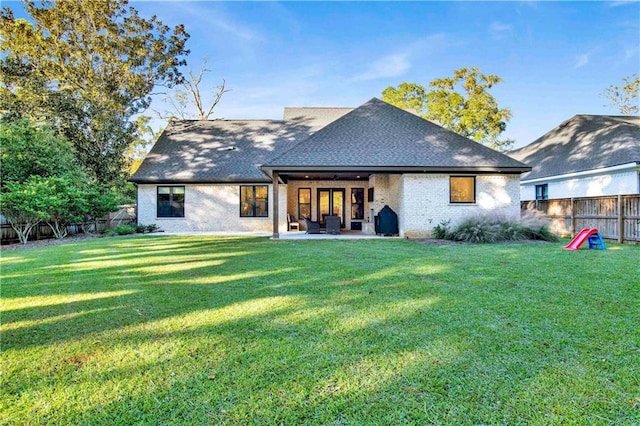 rear view of house with a patio and a lawn