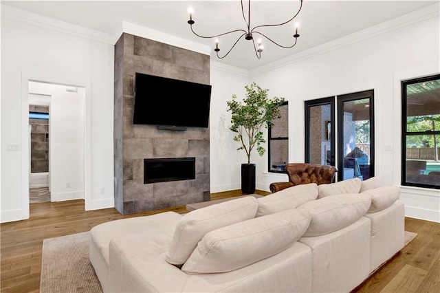 living room with a fireplace, hardwood / wood-style floors, an inviting chandelier, and ornamental molding