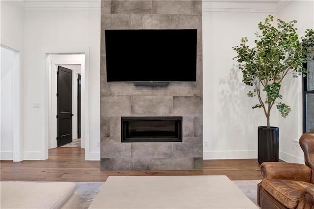 living room featuring hardwood / wood-style floors, a fireplace, and crown molding