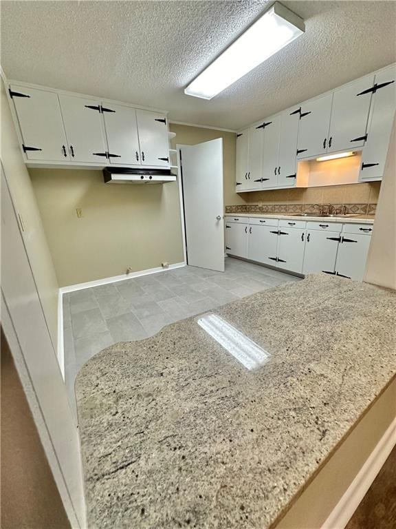 kitchen featuring a textured ceiling, white cabinets, and light tile floors