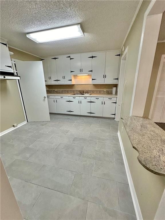 kitchen with white cabinetry, light tile flooring, a textured ceiling, and light stone countertops