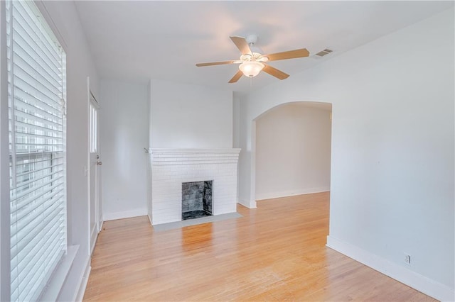1852 Old Shell Rd, Mobile, AL 36607 - unfurnished living room featuring arched walkways, ceiling fan, a fireplace, and light wood-style flooring