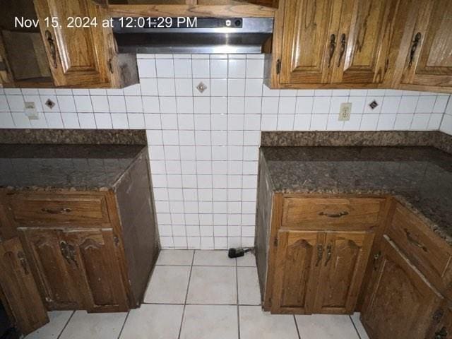 kitchen featuring dark stone countertops, light tile patterned floors, and extractor fan