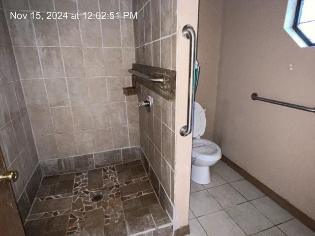 bathroom featuring tile patterned flooring, toilet, and a tile shower