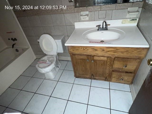 full bathroom with tile patterned floors, vanity, toilet, and tile walls