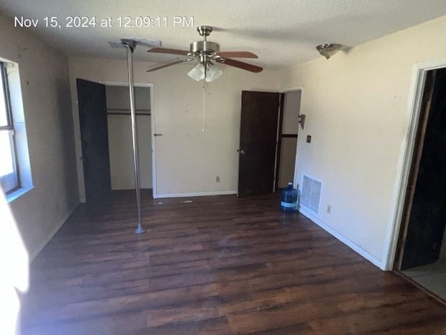 unfurnished bedroom featuring dark wood-type flooring, ceiling fan, a textured ceiling, multiple windows, and a closet