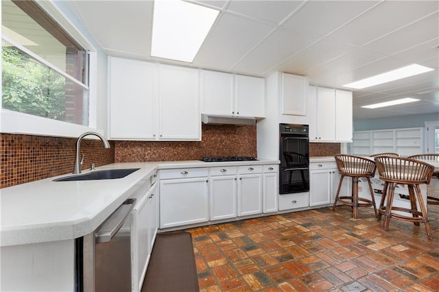 6659 Viking Way, Mobile, AL 36582 - kitchen featuring stainless steel dishwasher, brick patterned flooring, white cabinets, tasteful backsplash, and gas stovetop