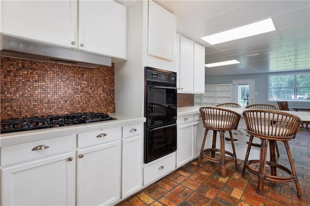 6659 Viking Way, Mobile, AL 36582 - kitchen with black appliances, under cabinet range hood, brick patterned floors, light countertops, and white cabinetry
