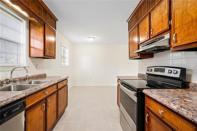 kitchen featuring dark stone countertops, stainless steel appliances, sink, and backsplash