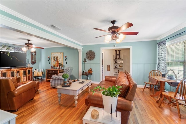 living room featuring light wood-type flooring, ornamental molding, and ceiling fan