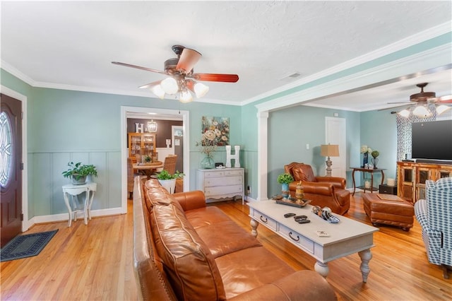 living room featuring ceiling fan, ornamental molding, and light wood-type flooring