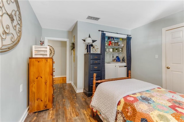 bedroom with dark hardwood / wood-style floors and washer and clothes dryer