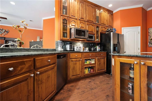 2765 Knollwood Dr, Mobile, AL 36693 - kitchen featuring appliances with stainless steel finishes, ornamental molding, dark wood finished floors, dark stone countertops, and glass insert cabinets