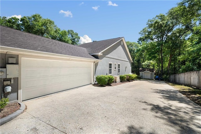 2765 Knollwood Dr, Mobile, AL 36693 - view of side of property featuring concrete driveway, a garage, stucco siding, and a shingled roof