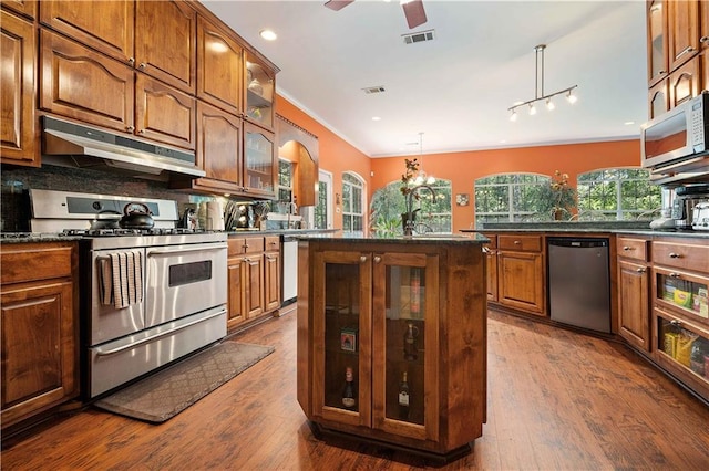 2765 Knollwood Dr, Mobile, AL 36693 - kitchen with stainless steel appliances, under cabinet range hood, dark countertops, backsplash, and crown molding