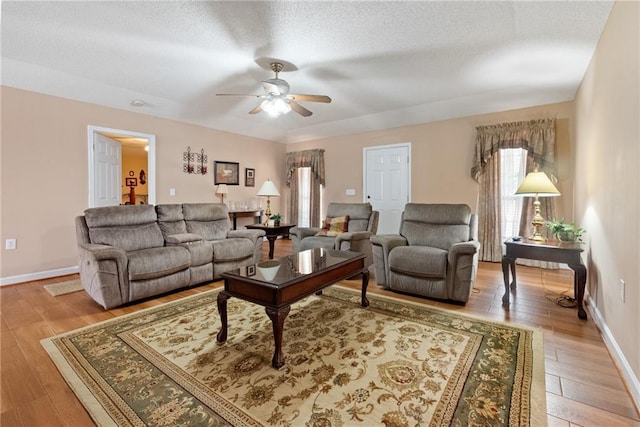 living room with ceiling fan, light hardwood / wood-style floors, and a textured ceiling