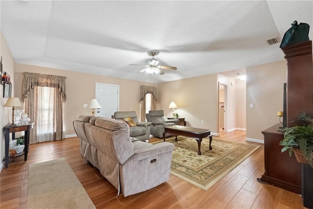 living room with ceiling fan, light hardwood / wood-style flooring, and a textured ceiling