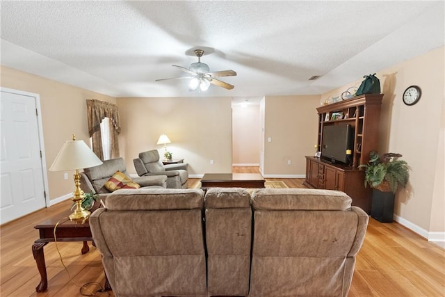 living room featuring a textured ceiling, ceiling fan, and light wood-type flooring