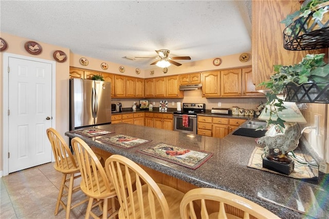 kitchen with sink, a textured ceiling, kitchen peninsula, ceiling fan, and stainless steel appliances