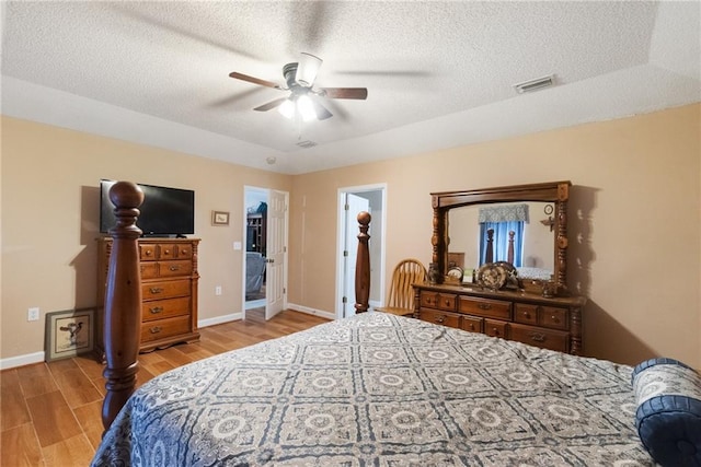 bedroom with ceiling fan, a textured ceiling, and light hardwood / wood-style flooring