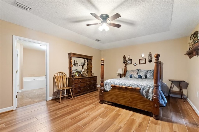 bedroom with wood-type flooring, ensuite bathroom, ceiling fan, and a textured ceiling