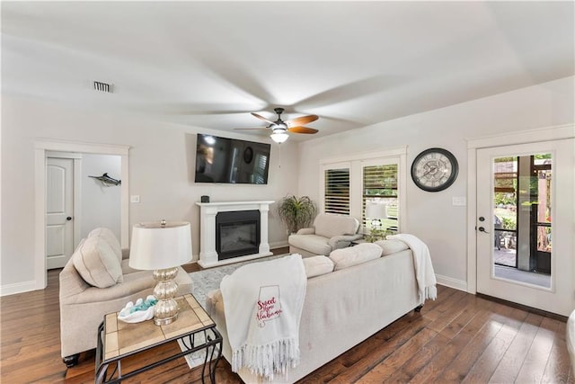living room featuring visible vents, a ceiling fan, dark wood finished floors, and baseboards