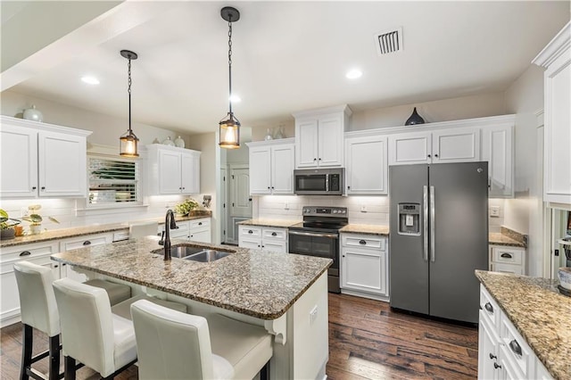 kitchen featuring a sink, stainless steel appliances, backsplash, white cabinetry, and an island with sink