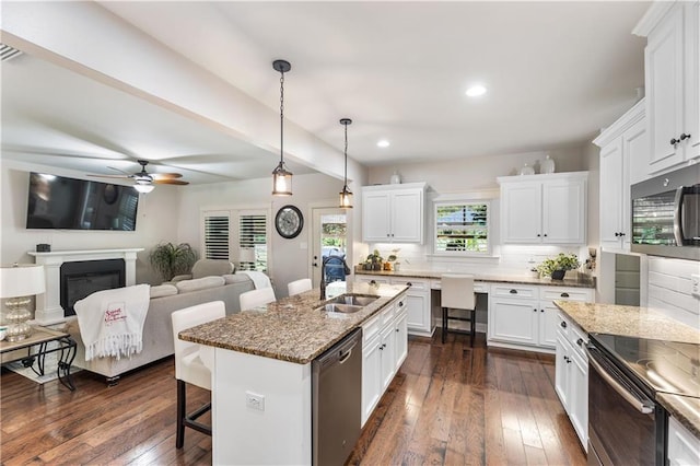 kitchen featuring recessed lighting, a breakfast bar area, appliances with stainless steel finishes, dark wood-style flooring, and a sink