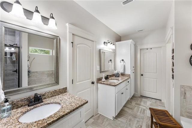 full bath featuring visible vents, two vanities, and a sink