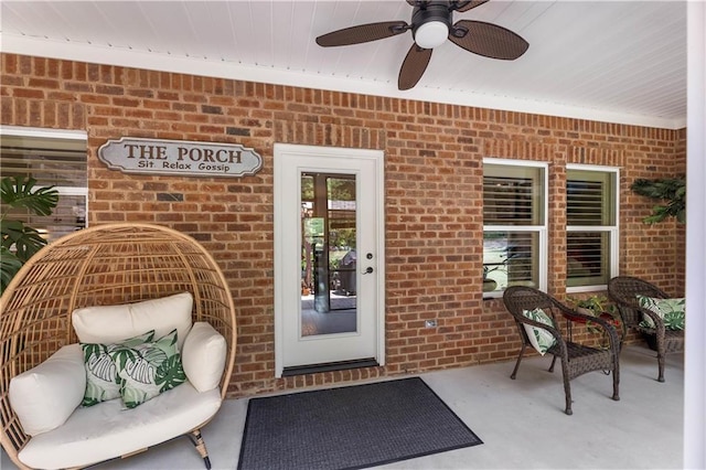 doorway to property with a ceiling fan and brick siding