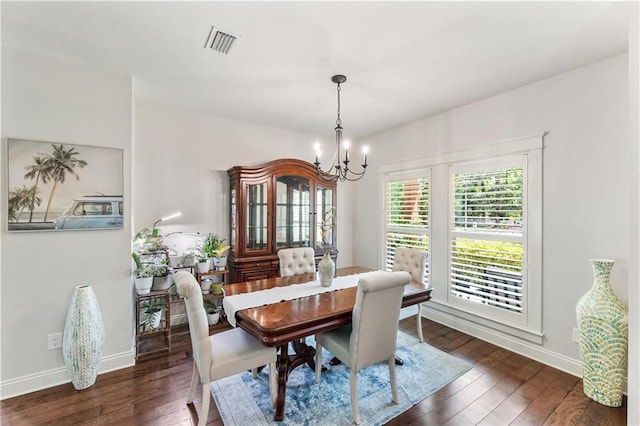 dining room with dark wood-type flooring, visible vents, a chandelier, and baseboards